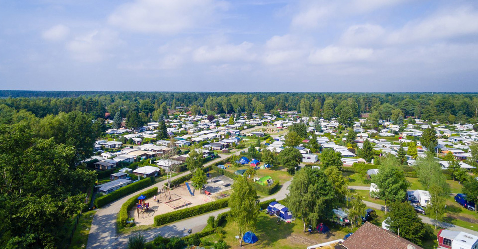 Luftaufnahme, des Campingplatzzentrums mit Zelthäusern, Wohnwagen und Zelten. 